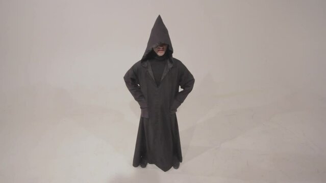Man in a funny executioner costume posing against the empty white wall background