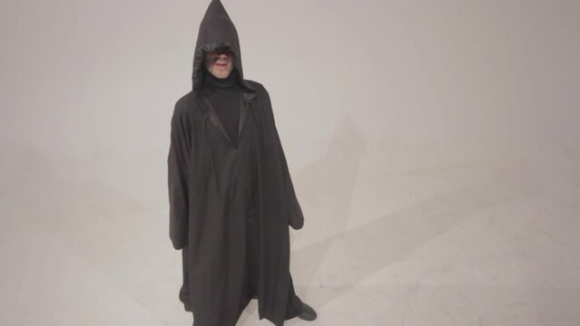 Man in a funny executioner costume posing against the empty white wall background