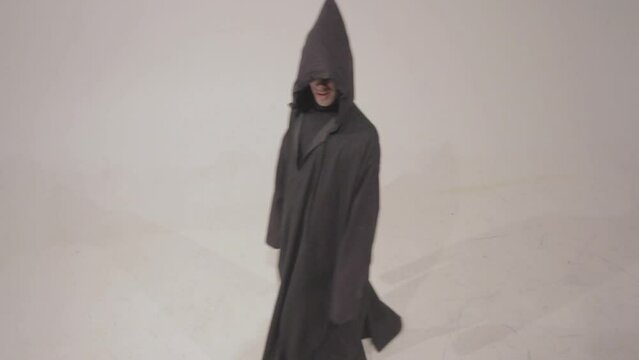 Man in a funny executioner costume posing against the empty white wall background