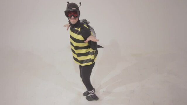 Man in a funny bee costume posing against the empty white wall background