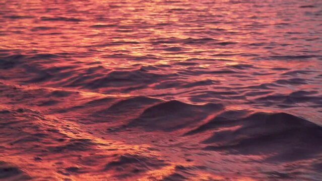 Slow-motion view from a boat driving on a wavy lake during a vibrant sunset
