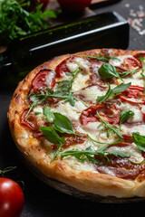 Pizza with ham,tomatoes and mozzarella on a dark background