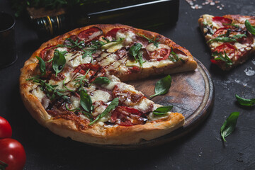 Pizza with ham,tomatoes and mozzarella on a dark background