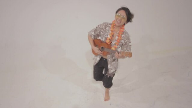 Funny girl with hawaiian beads playing guitar on a white background