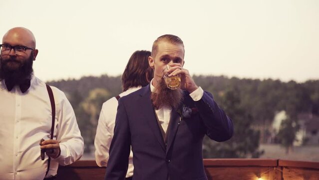 Caucasian groom with his cool friends smoking Cuban Cigars during the wedding event at sunset