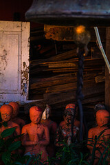 Red statues of people praying , with a bell in the foreground at Wat Phantao ( next to Wat chedi luang )