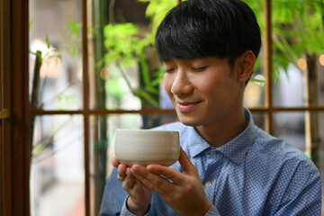 Close up with Young Asian man enjoying and holding tea cup, Japanese traditional matcha tea.