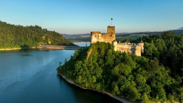Poland. Medieval castle in Niedzica in sunset light. Artificial Czorsztyn lake on Dunajec river, dam and hydro power station,. Tatra Mountains in the background. Aerial panning video