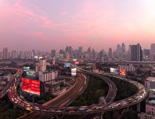 Panorama of Bangkok at dusk with skyscrapers in background & heavy traffic on elevated expressways & circular interchanges ~ Night scape of Bangkok with busy traffic on intertwined highway overpasses