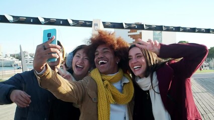 Group of multiethnic friends in winter clothes having fun taking a selfie in the city during winter