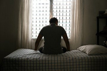 Desperate man in silhouette sitting on the bed alone. masculinity and emasculation concept.