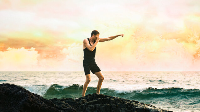 young man training his left hook by the sea - Powered by Adobe