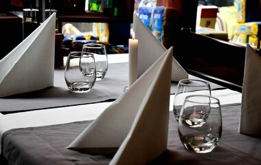 Pristine, white restaurant table with glasses of water and folded napkins