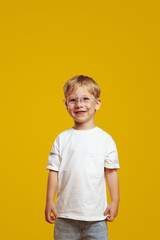 Happy cute pupil boy in stylish white t shirt and eyeglasses smiling and looking excited at camera