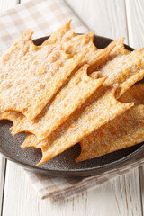 Oreillettes deliciously light and crisp pastry fritters closeup on the plate on the wooden table. Vertical