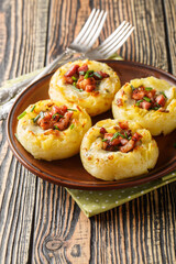 Potato nests cooked from mashed potatoes and baked with bacon and onions close-up in a plate on the table. Vertical