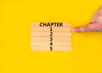 Time to chapter 1 symbol. Concept word Chapter 1 2 3 4 5 on wooden sticks. Businessman hand. Beautiful yellow table yellow background. Business planning and time to chapter 1 concept. Copy space.