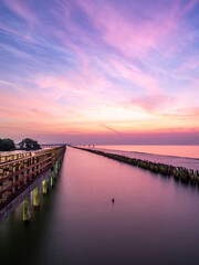 Sea view near mangrove forest with man made wooden barrier for wave protection, under morning twilight colorful sky in Bangkok, Thailand