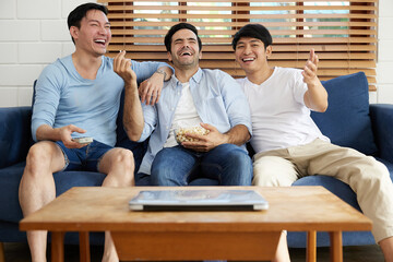 group of men watching tv and eating popcorn in living room