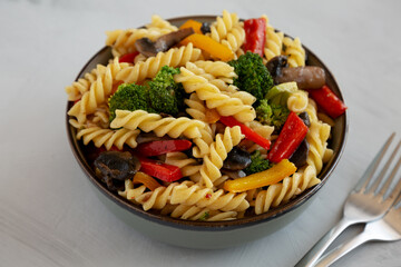 Homemade Garlic Veggie Rotini Pasta in a Bowl on a gray background, side view.
