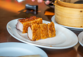 Crispy delicious pork on white dish in Chinese style restaurant in Bangkok, Thailand