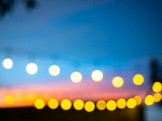 Blurred, out of focus, of light bulbs with twilight colorful sky in courtyard for background