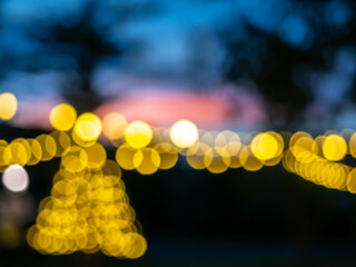 Blurred, out of focus, of light bulbs with twilight colorful sky in courtyard for background