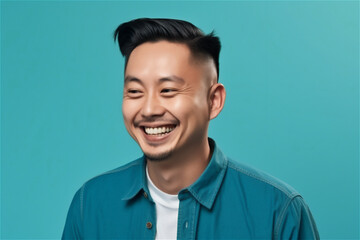 Fototapeta premium Asian young adult man smiling on a blue background