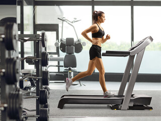 Fit young female running on a treadmill in a gym