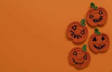 Handmade crochet Halloween pumpkins on an orange background. Copy space. Top view.