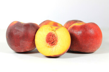 Fototapeta na wymiar close up of ripe red peaches one of which is cut in half, on a white background