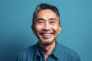 Asian mid adult man smiling on a blue background