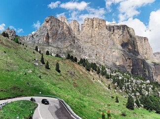 Magnificent scenery of Dolomiti under blue sky with rugged Sella group in background & cars...