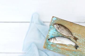 Two small fish on a wooden background, top view, free space, white background