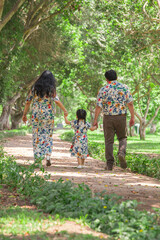 Family walking through the park on a shiny sunny summer day holding hands