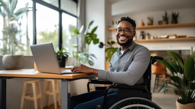 Middle-aged man in a wheelchair works from his home office.