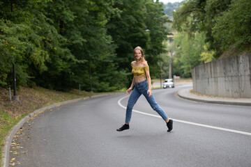 A young beautiful girl is jumping on a bend in the road
