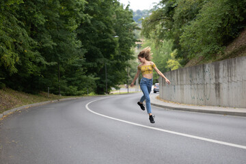 A young beautiful girl is jumping on a bend in the road