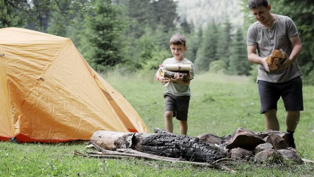 Young scout showing his son how to make campfire during trip in natural environment.