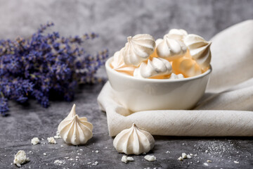Small white meringues in a white plate on a gray background