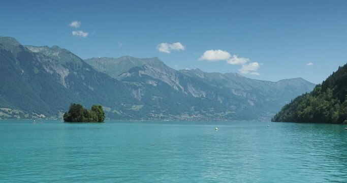 Swiss lake landscape. Calm waters of lake Brienz and the famous Bay of Iseltwald with Turtle Island (Schneckeninsel), Emmental Alps mountains and Brienzer Rothorn on horizon