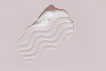 White beauty cream smear smudge on pink background. Cosmetic skincare product texture. Face cream,...