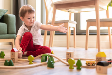 a boy of 4 years old plays a toy train at home on the floor in the living room