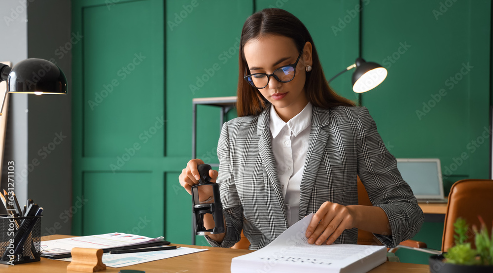 Wall mural Female notary public attaching seal to documents in office