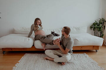 A man massages feet of a pregnant woman in a bright apartment - Powered by Adobe