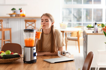 Young woman drinking healthy smoothie in kitchen