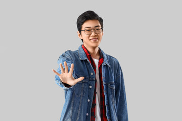 Young Asian man showing palm on light background