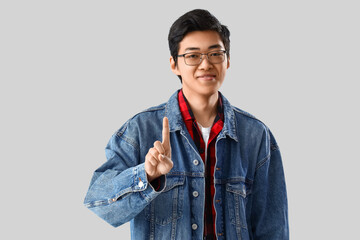 Young Asian man showing one finger on light background