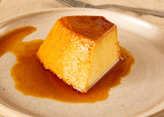 Creme Caramel Condensed Milk Pudim slice in front view with beige background