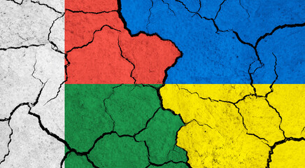 Flags of Madagascar and Ukraine on cracked surface - politics, relationship concept